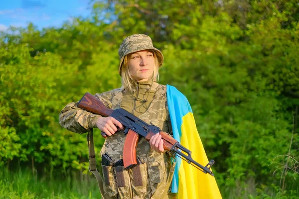 Портрет женщины-солдата с пистолетом и украинским флагом на плече, смотрящей в сторону — стоковое фото