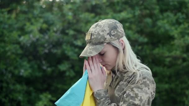 Female patriot soldier holds Ukrainian flag and praying with hope — Video Stock