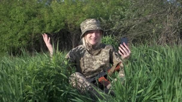 Mujer soldado con un rifle de asalto se comunica con alguien a través de videollamada — Vídeo de stock