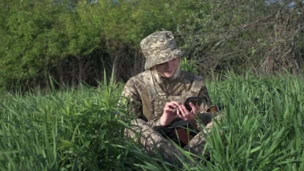 Mladá Ukrajinská Voják Maskovací Uniformě Útočnou Puškou Sedí Trávě Komunikuje — Stock video