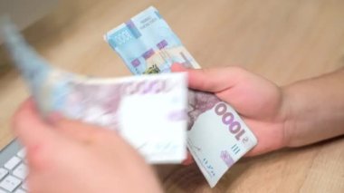 Tanımlanamayan beyaz adamın elleri Ukrayna 'ya ait binlerce Hryvnias banknotunu tutuyor ve sayıyor veya kontrol ediyor. Nakit para kavramı.