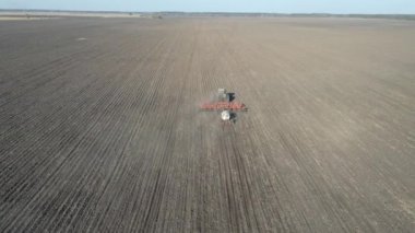 Aerial view of tractor with trailed agricultural machinery plowing and apply fertilizers in soil. Ammonia fertilizers are sprayed from nozzles into the ground