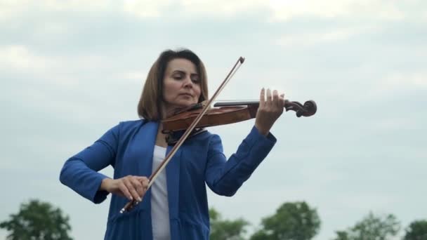 Low Angle Female Musician Playing Violin Gray Sky Trees High — Stockvideo