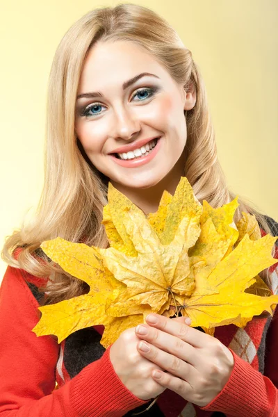 Beautiful young woman holds maple leaf — Stock Photo, Image