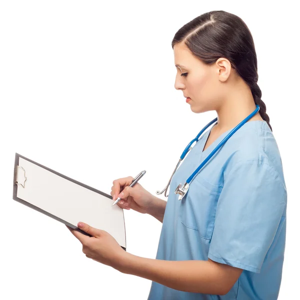 Serious young female doctor writing on clipboard — Stock Photo, Image