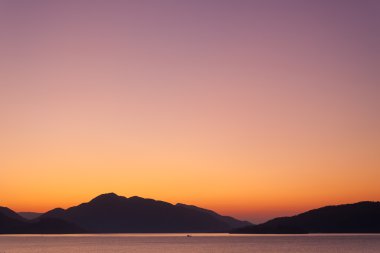 gün batımı. Deniz ve dağlar. pastel tonları.