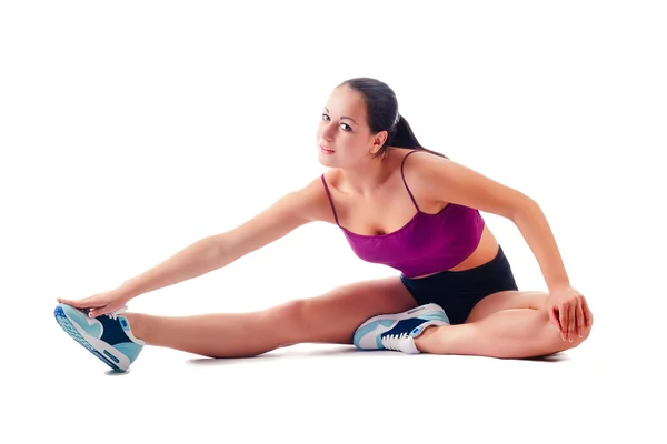 Beautiful woman in sportswear does exercises sitting on floor — Stock Photo, Image