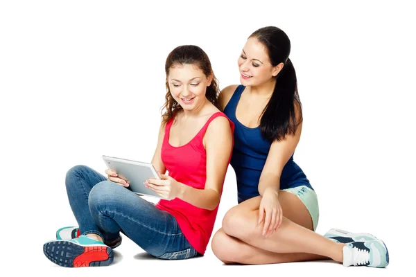 Two young sitting women looking in pad — Stock Photo, Image