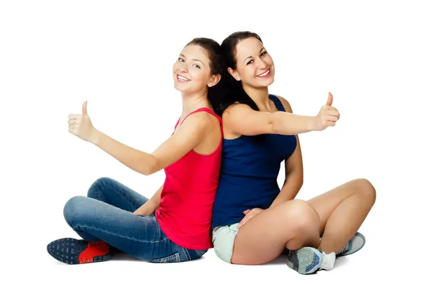 Duas mulheres jovens sentadas e mostrando sinal ok — Fotografia de Stock