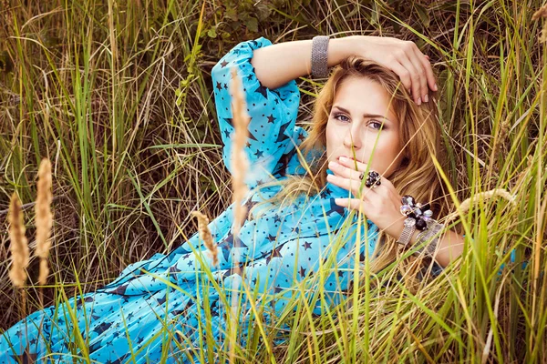 Mooie blonde vrouw in jurk ligt op gras — Stockfoto