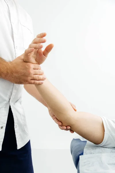 患者を治療する理学療法士のクローズアップ.オステオパスは人間の手を握ってる — ストック写真