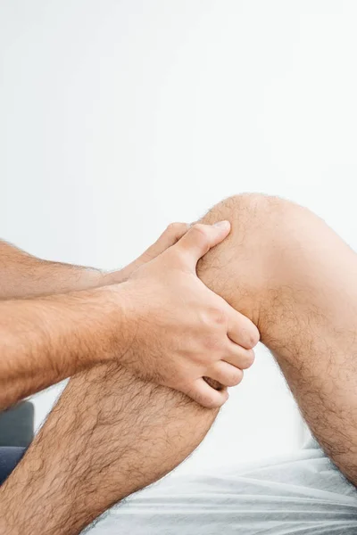 Een osteopaat onderzoekt de knie van een man die op een massagebank ligt — Stockfoto