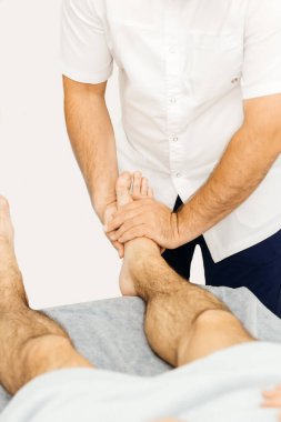 Osteopat bir adamın ayağını muayene eder.