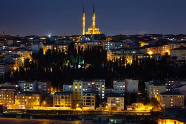 Aydınlanmış şehrin gece manzarası, aydınlatılmış evler ve cami. Pencerelerdeki ışıklar açık. İstanbul 'a yolculuk