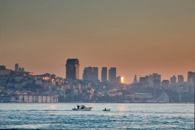 Şafakta deniz kıyısındaki evler. Denizden şehir manzarası, gün doğumunda tekneler, gökdelenler. İstanbul 'a yolculuk