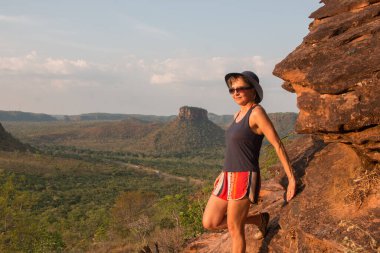 Brezilya, Maranhao 'daki Chapada da Mesas' ta güneş batarken kırmızı kayalıklara vuran kadın.