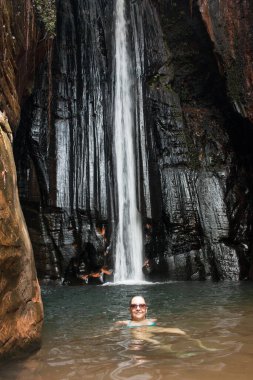Brezilya 'nın Maranhao eyaletinde, Carolina şehrinin yakınlarındaki Pedra Caida' nın içinde Şelale Cachoeira Capelao 'da eğlenen bir kadın.