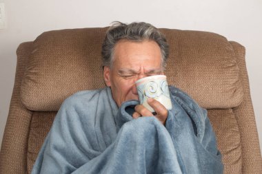 Olgun Adam kendini iyi hissetmiyor Battaniyeye sarılı çay içiyor
