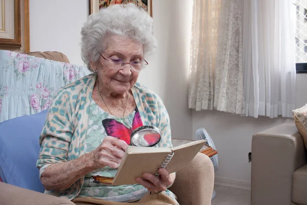 Senhora Idosa Casa Sentada Uma Cadeira Lendo Livro Usando Uma — Fotografia de Stock