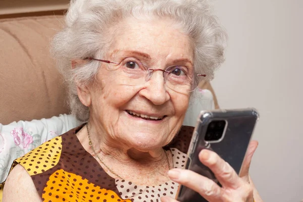 Пожилая Дама Дома Сидит Кресле Смотрит Свой Смартфон — стоковое фото