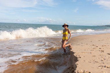 Arraial d Ajuda, Bahia, Brezilya 'da Pitinga olarak bilinen plajda, sarı bikinili kadınlar. 