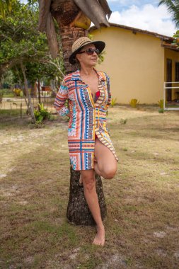 Caraiva, Bahia, Brezilya 'da plajın yakınındaki bir palmiye ağacına yaslanmış bir kadın.