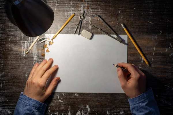 Tahta masa üzerine boş çarşaf ve üzerinde taslak, kalem, silgi ve eller için mühendislik araçları olan bir model..