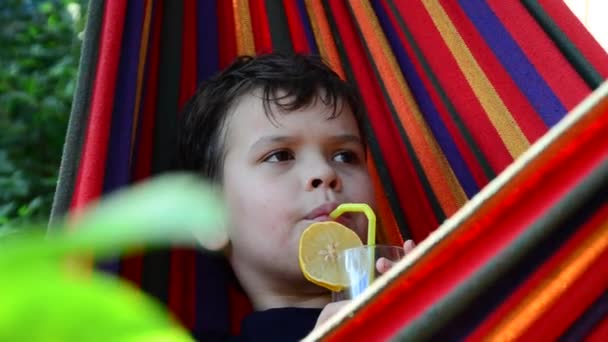 Chłopiec odpoczywający w hamaku w naturze, pijący koktajl z cytryną. nastolatek relaks w Hamaku. koncepcja urlopu — Wideo stockowe