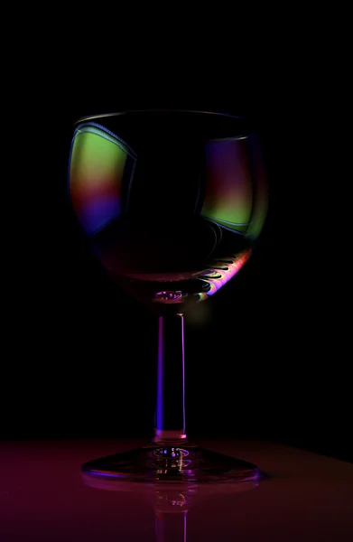 Un bicchiere vuoto su sfondo nero con bordi arcobaleno — Foto Stock