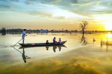 Tay Ninh, Vietnam - December 8th, 2021: The ferryman rowed a boat to take guests through the wetlands to return home at sunset, the idyllic rural life in Tay Ninh, Vietnam