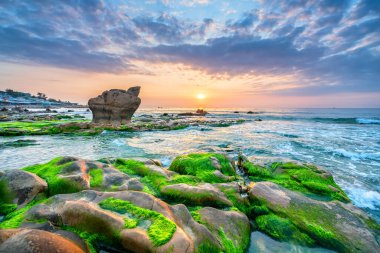 Rocky plajı ve yeşil yosun gündoğumunda gökyüzünde Orta Vietnam 'da güzel bir plajda
