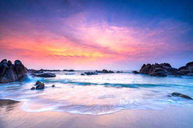 Güneşin doğuşunda güzel bir sahil. Dalgaların altında. Huzurlu yeni güne hoş geldin demek için yumuşak büyük sahilde tur atıyor.