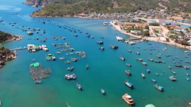 Vinh Hy Bay in Ninh Thuan, Vietnam viewed from above at noon in summer with hundreds of fishing boats moored and fishing villages below.