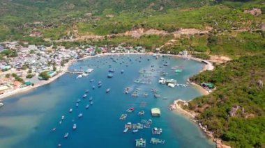 Vinh Hy Bay in Ninh Thuan, Vietnam viewed from above at noon in summer with hundreds of fishing boats moored and fishing villages below.