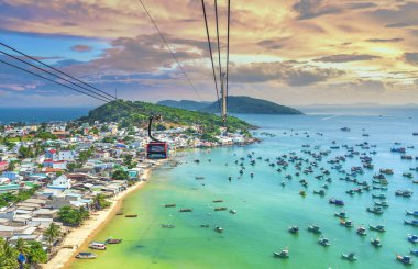 Dünyanın en uzun teleferik yolculuğu Güney Vietnam 'daki Phu Quoc adası, günbatımı gökyüzü. Aşağıda, popüler Hon Thom adasındaki An Thoi kasabasının limanında sıralanmış geleneksel balıkçı tekneleri var.. 