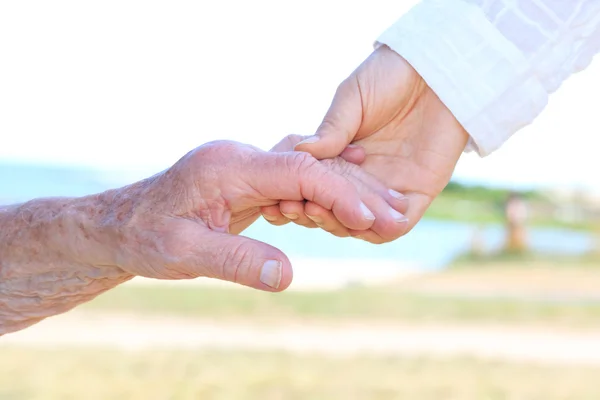 Unga och äldre kvinnor hand i hand — Stockfoto