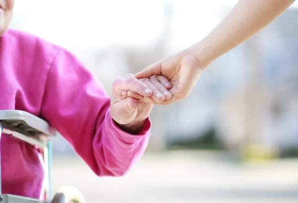 Senior dame in rolstoel hand in hand Rechtenvrije Stockfoto's