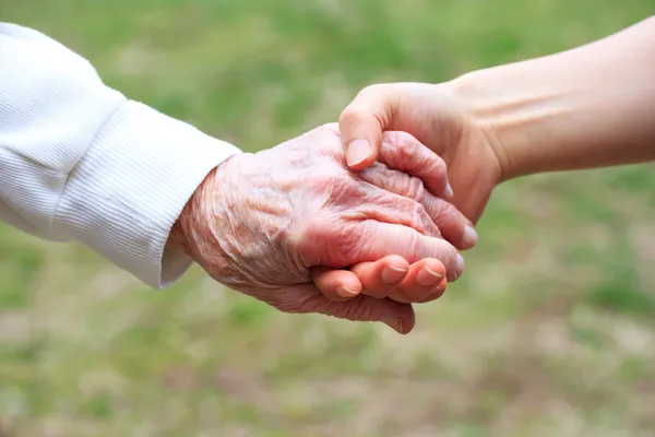 Äldre och unga kvinnor hand i hand — Stockfoto