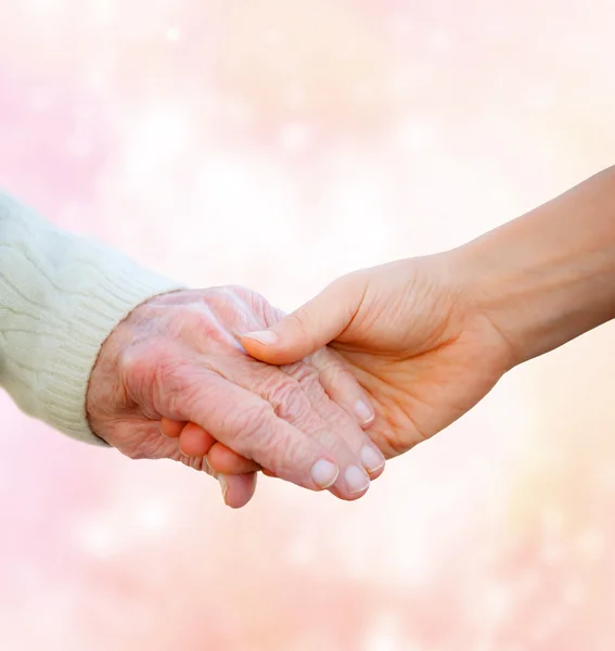 Ηλικιωμένης, κρατώντας τα χέρια με νεαρή γυναίκα — Φωτογραφία Αρχείου
