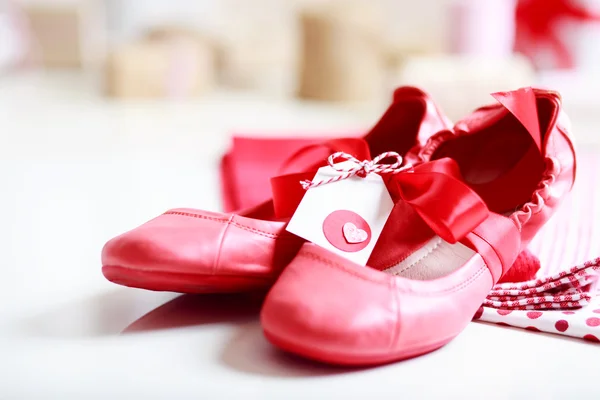 Red shoes with ribbon and heart tag — Stock Photo, Image