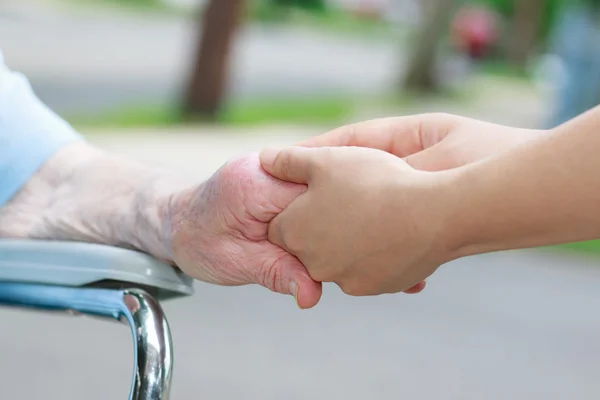 Смотритель держит пожилых женщин за руку — стоковое фото
