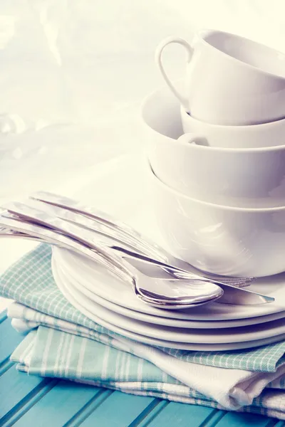 Witte borden en kopjes op blauwe servetten — Stockfoto