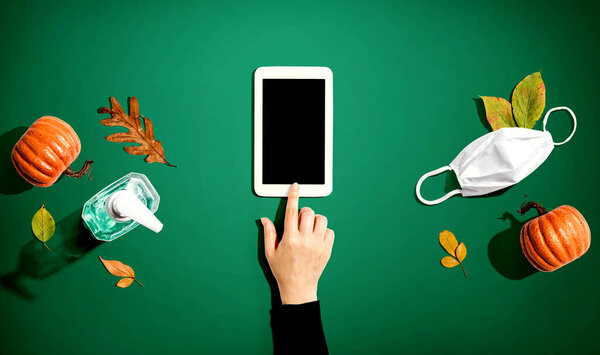 Tablet with a mask and a sanitizer bottle in Autumn