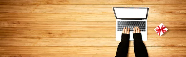Persoon die een laptop met een geschenkdoos gebruikt — Stockfoto