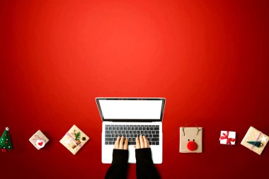 Noel hediyesi kutuları olan bir dizüstü bilgisayar kullanan kişi.