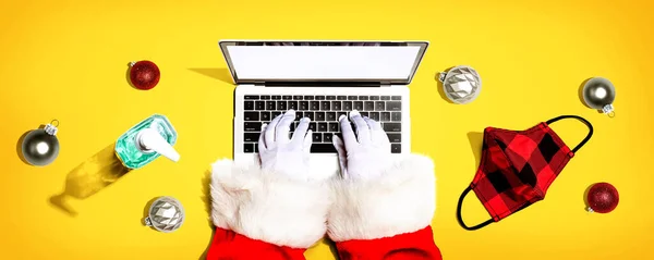 Święty Mikołaj za pomocą laptopa z maską i butelką środka dezynfekującego — Zdjęcie stockowe