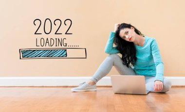 Yeni yıl 2022 'de dizüstü bilgisayar kullanan bir kadınla yükleniyor
