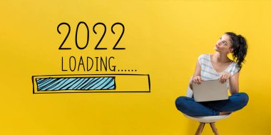 Yeni yıl 2022 'de dizüstü bilgisayar kullanan bir kadınla yükleniyor