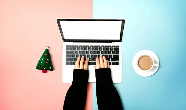 Πρόσωπο που χρησιμοποιεί φορητό υπολογιστή με μαξιλάρι χριστουγεννιάτικου δέντρου και φλιτζάνι καφέ — Φωτογραφία Αρχείου