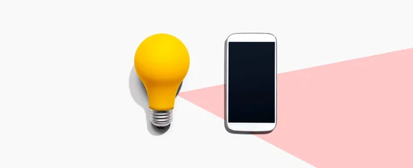 노란 전구가 달린 스마트폰 — 스톡 사진